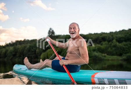 Senior man paddleboarding on lake in summer. Copy space. Senior man paddleboarding on lake in summer. Copy space. 75064833