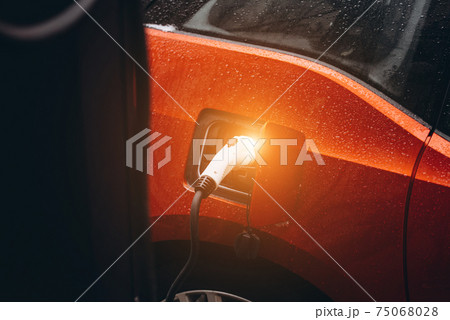 Electric car with power cable supply plugged in 75068028