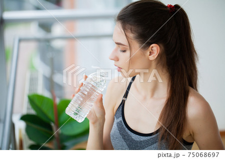 Young woman drinking water, beautiful young girl holding bottle of water 75068697