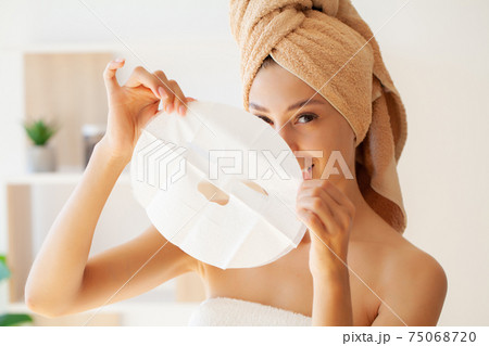 Pretty girl wearing face care mask at home 75068720