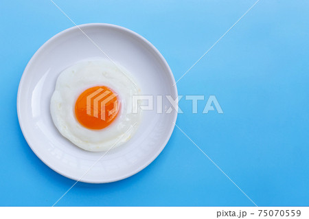 Fried egg on blue background. 75070559