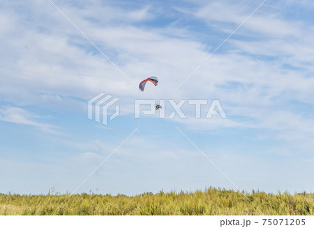 Moto-paraglider on green grass with blue sky. Moto-paraglider on green grass with blue sky. 75071205