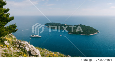Lokrum is a small island in the Adriatic Sea, near Dubrovnik, Croatia. A small cruise ship moored near the island. View from the observation deck from the mountain above Dubrovnik. 75077464