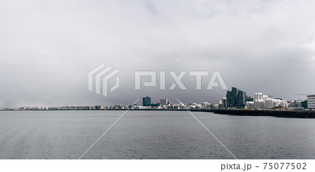 Multi-storey modern high-rise buildings on the waterfront in Reykjavik, the capital of Iceland. The shore of the Atlantic Ocean, the quiet water is calm. Cloudy sky, a blizzard is approaching. Multi-storey modern high-rise buildings on the waterfront in Reykjavik, the capital of Iceland. The shore of the Atlantic Ocean, the quiet water is calm. Cloudy sky, a blizzard is approaching. 75077502