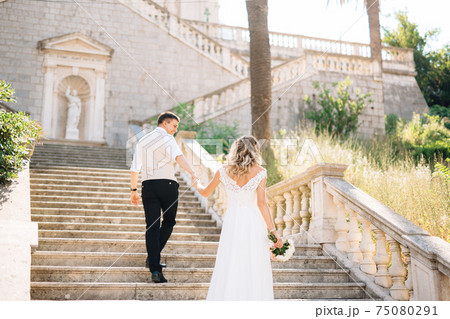 The bride and groom climb the ancient stairs of the Nativity of the Blessed Virgin Mary church in Prcanj 75080291