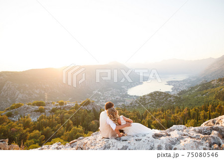 The bride and groom are embracing on Mount Lovcen, a picturesque panoramic view of the Bay of Kotor opens in front of them  75080546