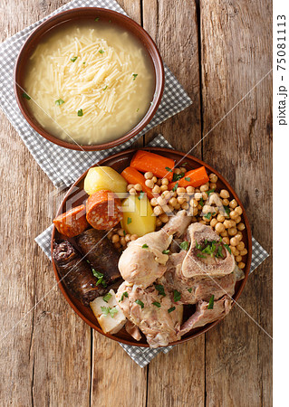 Madrid cocido meat, potato and chickpea stew close-up on a plate. Vertical top view 75081113