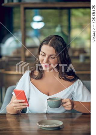 Involved joyful woman looking into smartphone in cafe 75086300