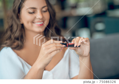 Admiring woman with lip gloss in hands 75086326