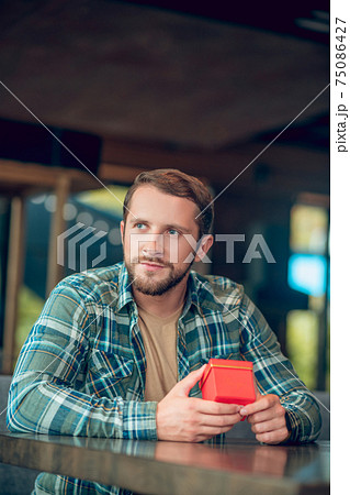 Pensive happy man with gift in cafe 75086427