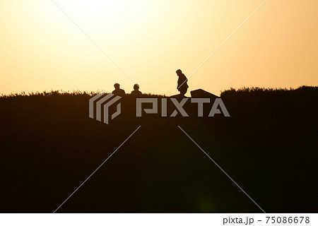 暮れなずむ古墳を散策する人たちのシルエットの美しい風景 75086678
