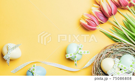 Easter eggs Colourful egg with tape ribbon, spring tulips, white feathers on pastel yellow background in Happy Easter decoration. Festive decoration in flat lay. Easter eggs Colourful egg with tape ribbon, spring tulips, white feathers on pastel yellow background in Happy Easter decoration. Festive decoration in flat lay. 75086808