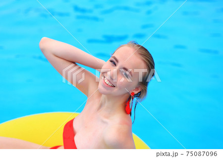 A beautiful young girl lies on an inflatable mattress in the summer water park. 75087096