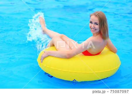 A beautiful young girl lies on an inflatable mattress in the summer water park. A beautiful young girl lies on an inflatable mattress in the summer water park. 75087097