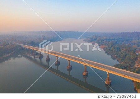 Aerial view of a bridge road street with Mekong River with green mountain hill and mist fog. Nature landscape background in Ubon Ratchathani, Thailand. Loas 75087453