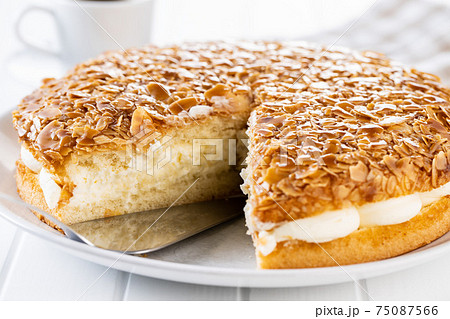 Sliced sweet almond cake on plate. Pie with cream and almonds. 75087566