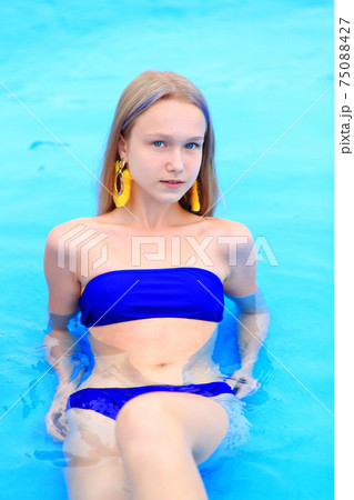 A beautiful young girl lies on an inflatable mattress in the summer water park. 75088427