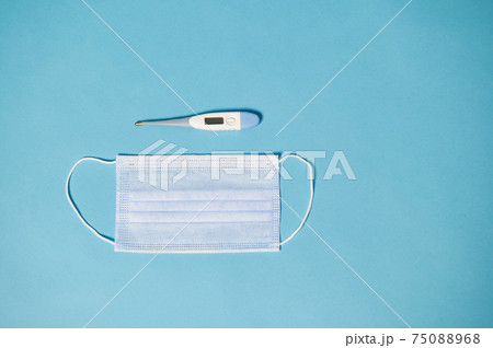 High angle view of protective medical mask and thermometer on blue background with copy space High angle view of protective medical mask and thermometer on blue background with copy space 75088968