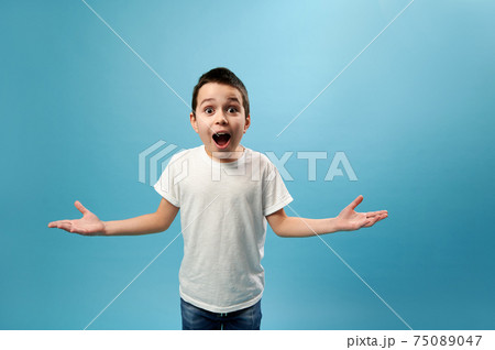 Shocked boy expressing surprise on camera. Facial emotions on blue background Shocked boy expressing surprise on camera. Facial emotions on blue background 75089047