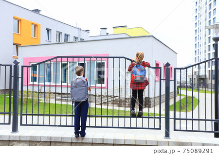 Children with briefcases over their shoulders on the background of the school. 75089291