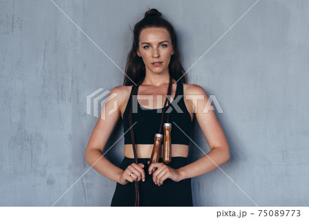 Sporty woman with a jump rope looks at the camera Sporty woman with a jump rope looks at the camera 75089773