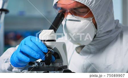 Close up of chemist doctor analysing virus using microscope 75089907