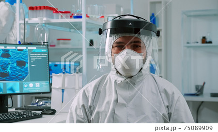 Overworked chemist sitting in equipped lab wearing coverall 75089909