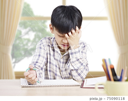 10 year-old asian elementary schoolboy appears to be frustrated while doing homework at home 10 year-old asian elementary schoolboy appears to be frustrated while doing homework at home 75090118