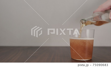 Slow motion pour orange drink in tumbler glass on walnut table with copy space 75090683