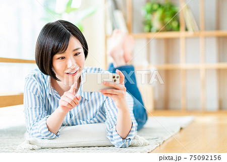 スマホで動画を見る若い女性 スマホで動画を見る若い女性 75092156