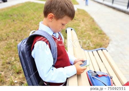 A boy in a school uniform with a backpack over his shoulders A boy in a school uniform with a backpack over his shoulders 75092551