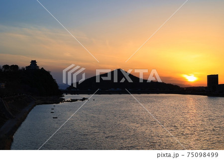 オレンジ色に染まる夕焼けと、犬山城と伊木山のシルエット 75098499