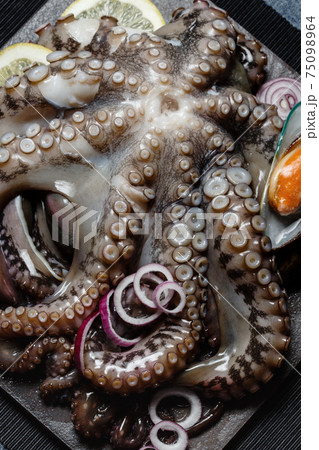 Seafood, whole raw big octopus on a stone dish served with mussels, lemon and red onion 75098964