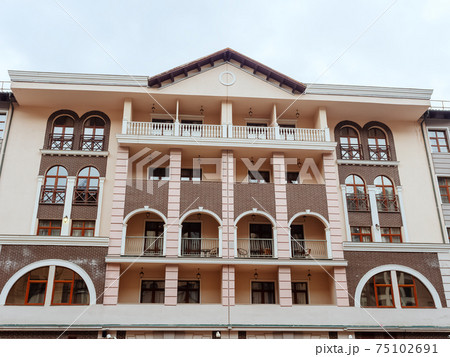 Beige brown building with arched windows and balconies and a triangular roof Beige brown building with arched windows and balconies and a triangular roof 75102691