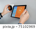 Man is Adjusting a  temperature using a tablet with a smart home app in modern living room 75102969