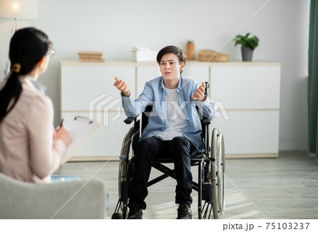 Professional psychological help for disabled teens. unhappy handicapped adolescent talking to psychotherapist at office 75103237