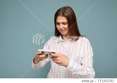 Concentrated attractive young blonde woman wearing casual white shirt isolated over blue background 75103292