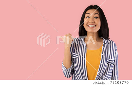 Excited asian woman pointing aside at copy space Excited asian woman pointing aside at copy space 75103770