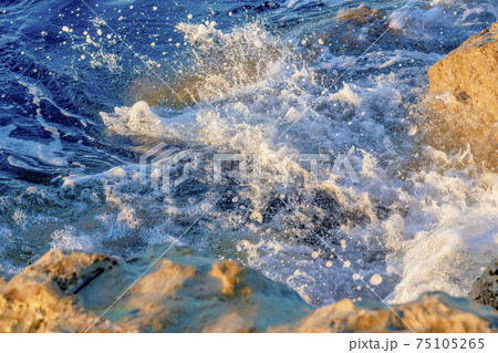 Waves crushing on the rocks on beach in the morning time. Sunrise on the wavy sea with rocks.  75105265
