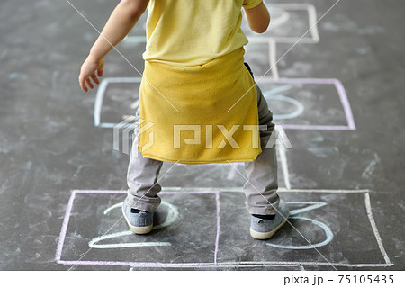 Little boy's jump on hop scotch drawn on asphalt. Little boy's jump on hop scotch drawn on asphalt. 75105435