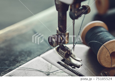 Close up of sewing needle. Spool of thread on working part of antique sewing machine. Close up of sewing needle. Spool of thread on working part of antique sewing machine. 75105524