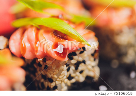 Maki Sushi Rolls with salmon on black stone on dark background. With ginger and wasabi. Sushi menu. Japanese food. Closeup of delicious japanese food with sushi roll. Horizontal photo. Maki Sushi Rolls with salmon on black stone on dark background. With ginger and wasabi. Sushi menu. Japanese food. Closeup of delicious japanese food with sushi roll. Horizontal photo. 75106019