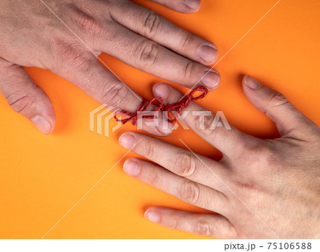 Memory and Reminder Knot. Female and male hands on an orange background 75106588