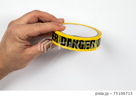 DANGER, yellow warning tape in a man's hands on a white background 75106715