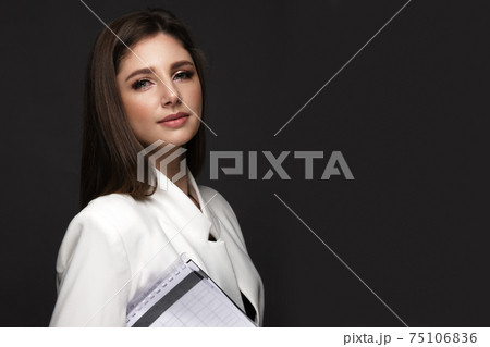 Business woman in a working uniform with a notebook in her hands. Business woman in a working uniform with a notebook in her hands. 75106836