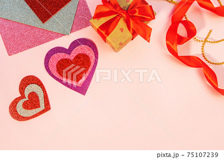 Packaging Valentine's Day or birthday presents. Valentine's Day gifts with a red paper heart on a pink background. Top view. 75107239