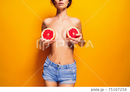 Crop woman holding grapefruit near breasts Crop woman holding grapefruit near breasts 75107250