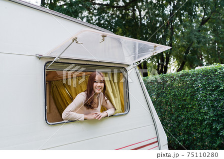 happy woman at window of a camper RV van motorhome 75110280