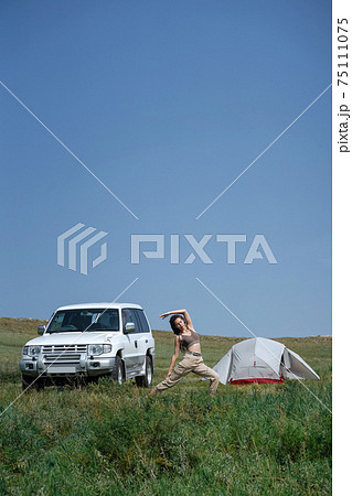 Girl doing yoga near white off road car and a tent Girl doing yoga near white off road car and a tent 75111075