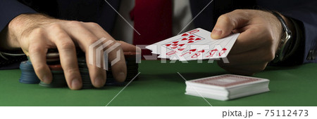 Businessman at green playing table with gambling chips and cards playing poker and blackjack in casino Businessman at green playing table with gambling chips and cards playing poker and blackjack in casino 75112473
